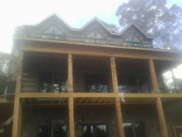 Dormers and porch framing on a large log home under construction — Roof Coating work by our crew in Bernalillo