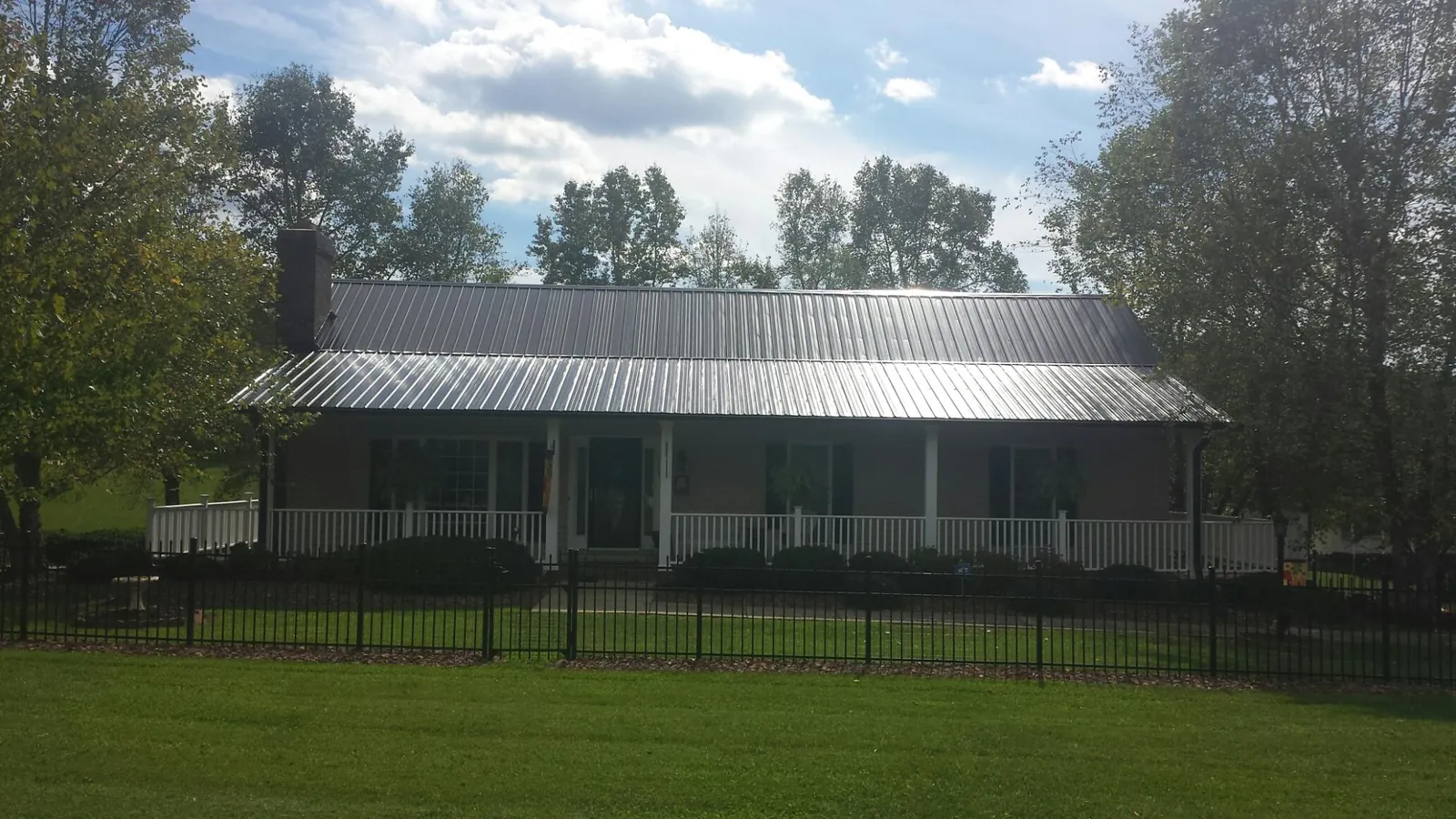 Gray metal roof on a brick ranch with a full width front porch — Gutter Guard Installation work by our crew in Bernalillo