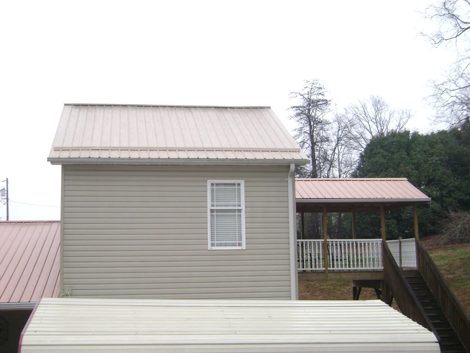 Tan metal roofs on a two story addition and attached porch, from a Roof Replacement job in Bernalillo