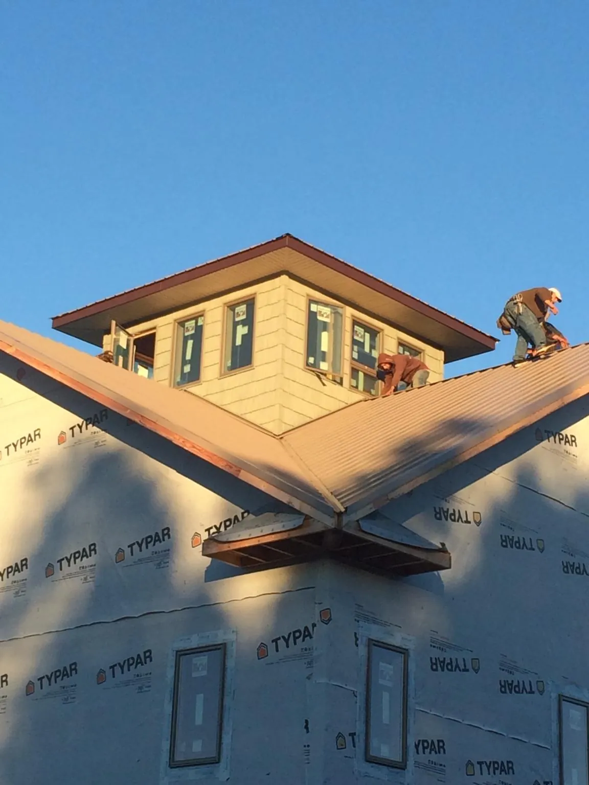 Roofers working around a rooftop cupola on a new metal roof at sunset — Roof Waterproofing in Bernalillo by Roofing Brothers